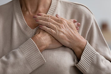 A woman holding her chest with her hands.
