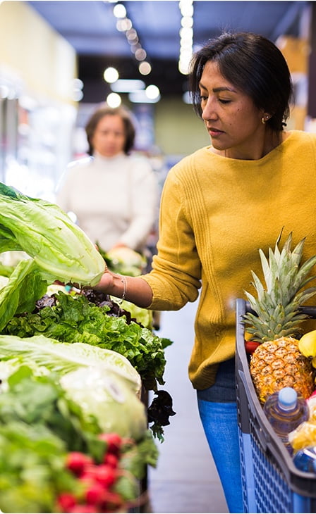 Personne choisissant des fruits et légumes à l’épicerie.