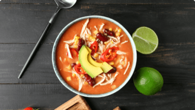 Cooked chicken enchilada soup in a bowl with limes on the side. Cooked chicken enchilada soup in a bowl with limes on the side.
