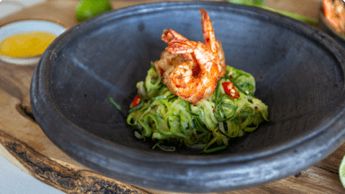 Crevettes des Antilles sur des nouilles de courgette dans un bol avec sauce à la mangue à côté. Crevettes des Antilles sur des nouilles de courgette dans un bol avec sauce à la mangue à côté.