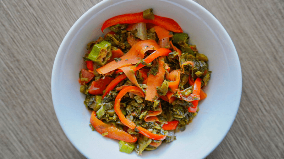 Colourful medley of cooked callaloo, okra and peppers in a bowl.