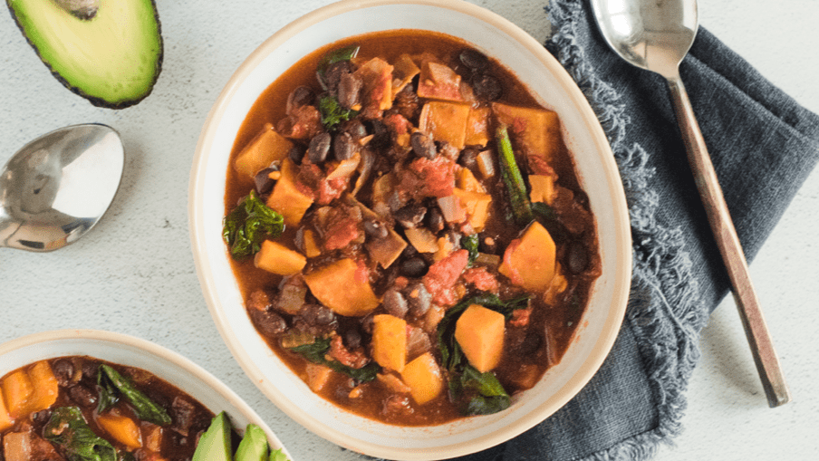 Chili à la patate douce et aux haricots noirs dans un bol garni et prêt à servir. Chili à la patate douce et aux haricots noirs dans un bol garni et prêt à servir.