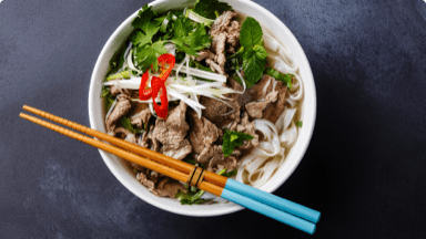 Beef noodle soup with garnish in a bowl ready to be eaten with chopsticks. Beef noodle soup with garnish in a bowl ready to be eaten with chopsticks.