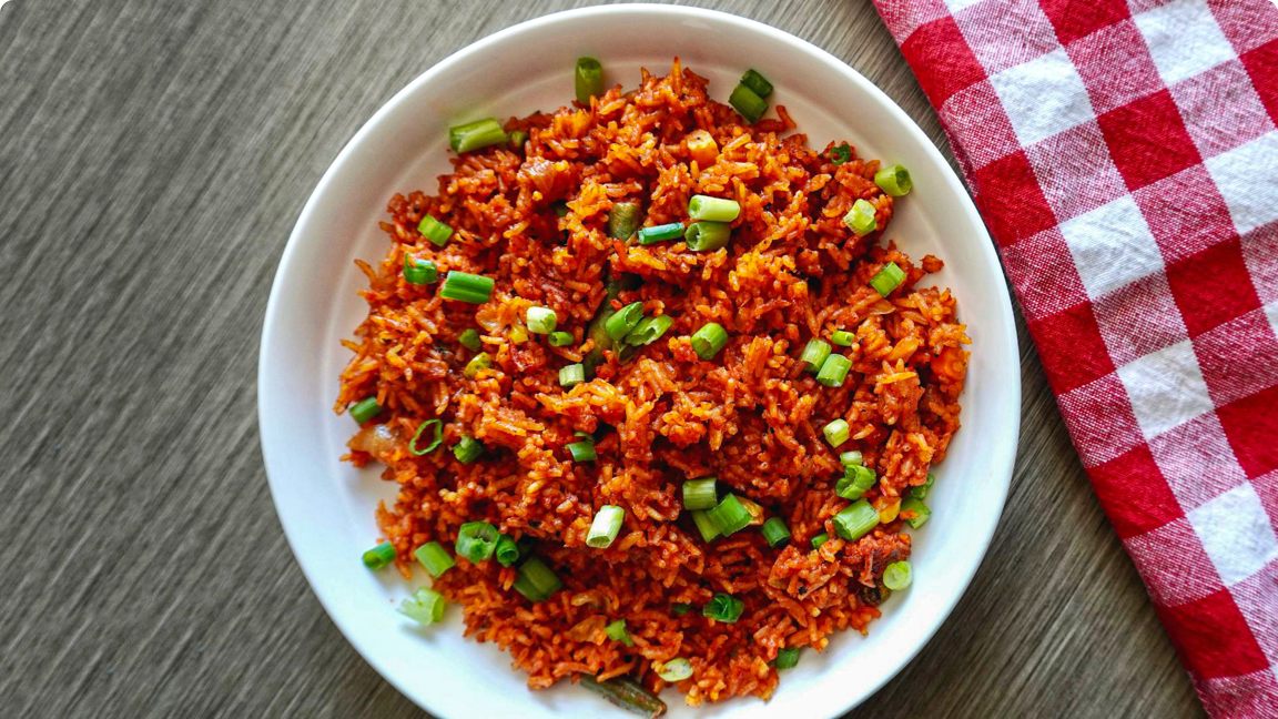Jollof rice in a bowl garnished with green onions, ready to be served.