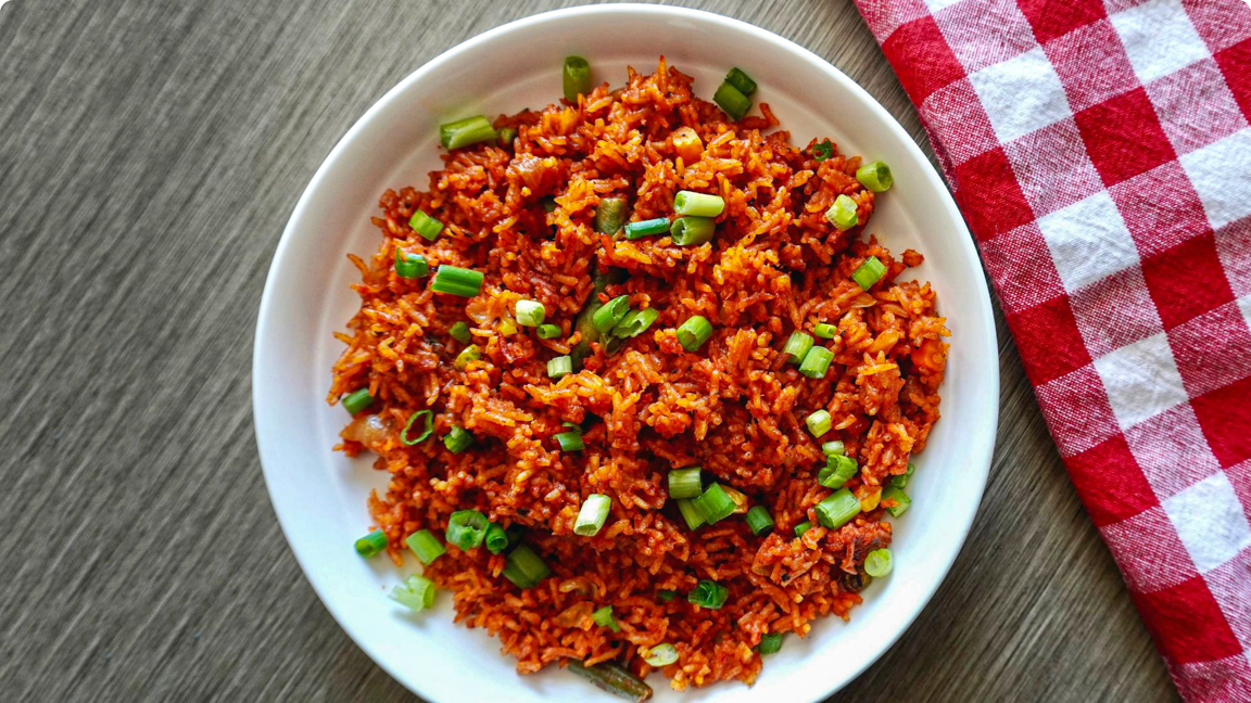 Jollof rice in a bowl garnished with green onions, ready to be served. Jollof rice in a bowl garnished with green onions, ready to be served.